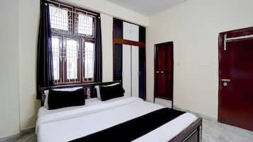 Una habitación con cama, ventana con rejas, armario y puerta.