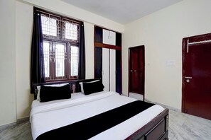 Una stanza con un letto, una finestra con sbarre, un armadio e una porta.