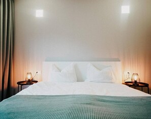Une chambre d’hôtel avec un grand lit, deux tables de chevet et une fenêtre avec des rideaux.