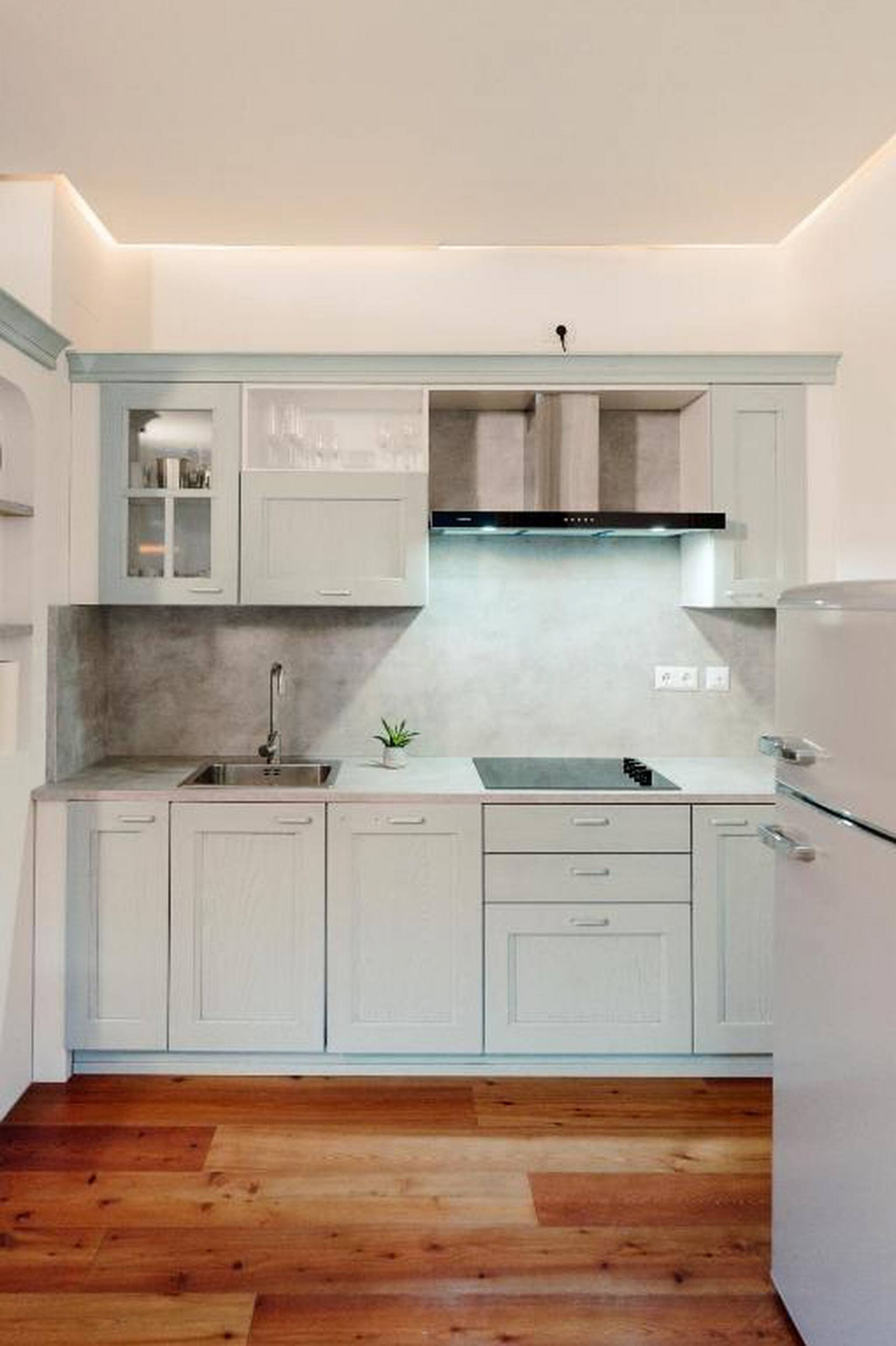 A compact kitchen with white cabinetry, a stainless steel sink, and a built-in oven.