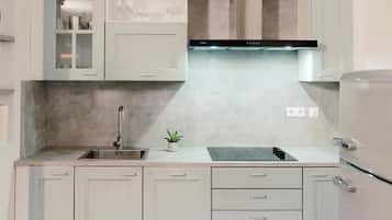 A compact kitchen with white cabinetry, a stainless steel sink, and a built-in oven.