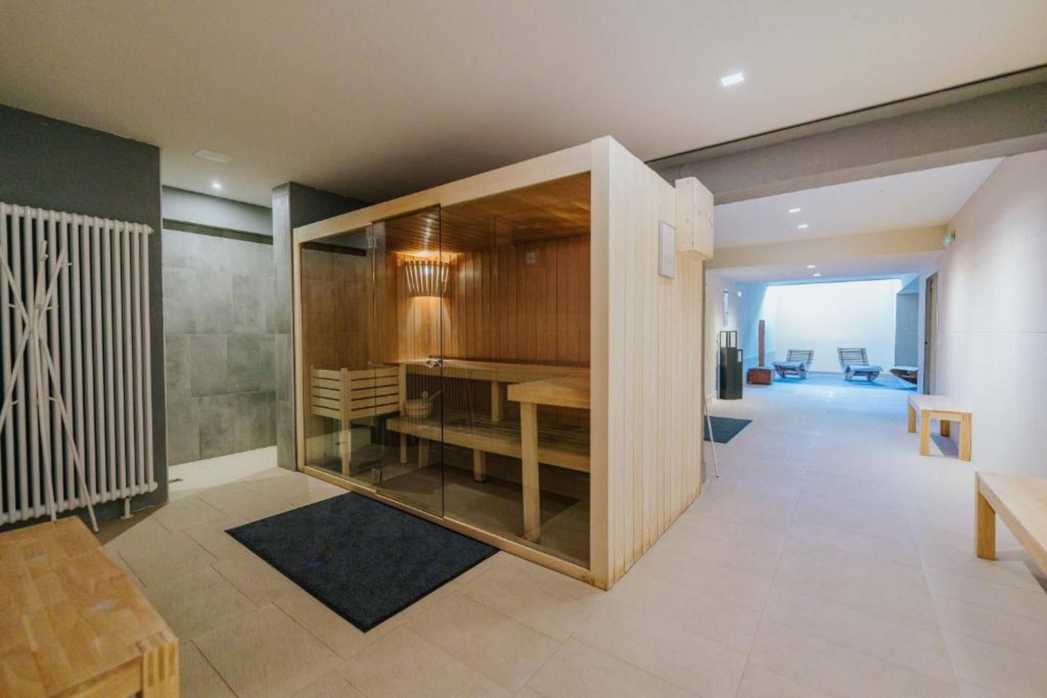 A modern interior with a sauna, a wooden bench, and a glass partition.