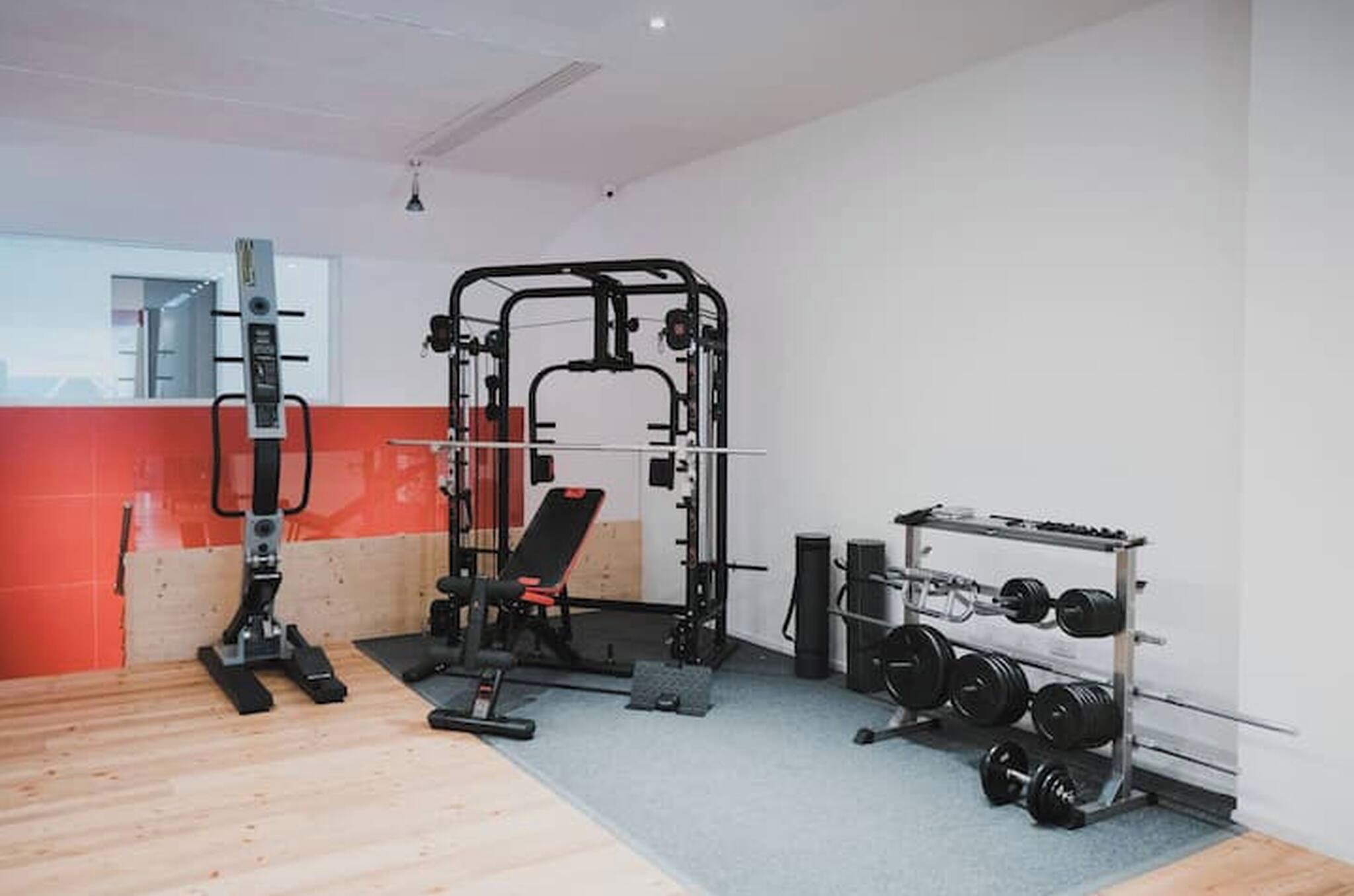 A gym with a squat rack, bench press, and weight plates.