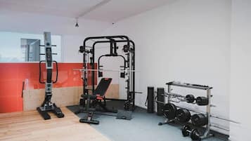 A gym with a squat rack, bench press, and weight plates.