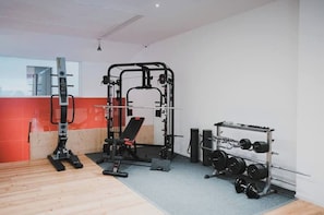 A gym with a squat rack, bench press, and weight plates.