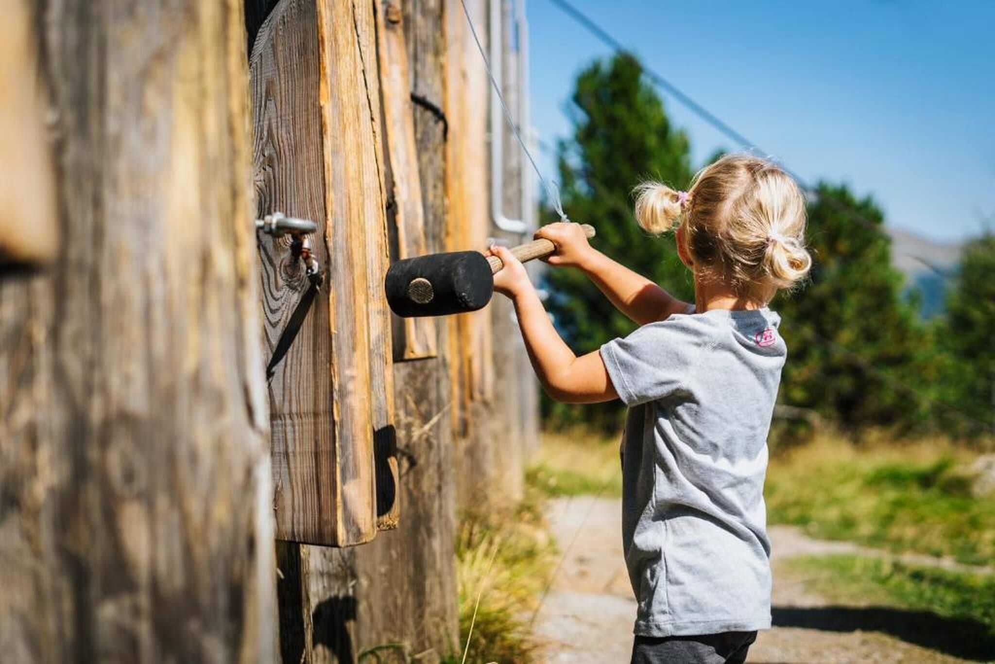 Un niño usando un martillo sobre una estructura de madera.