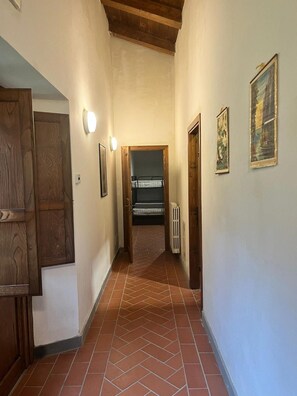 A corridor with a tiled floor, wooden doors, and framed pictures on the walls. - Casa Stabbi with Mountain View, Private Garden, and Air Conditioning (Chitignano)