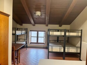 A dormitory room with bunk beds, a window, and a wooden table. - Casa Stabbi with Mountain View, Private Garden, and Air Conditioning (Chitignano)
