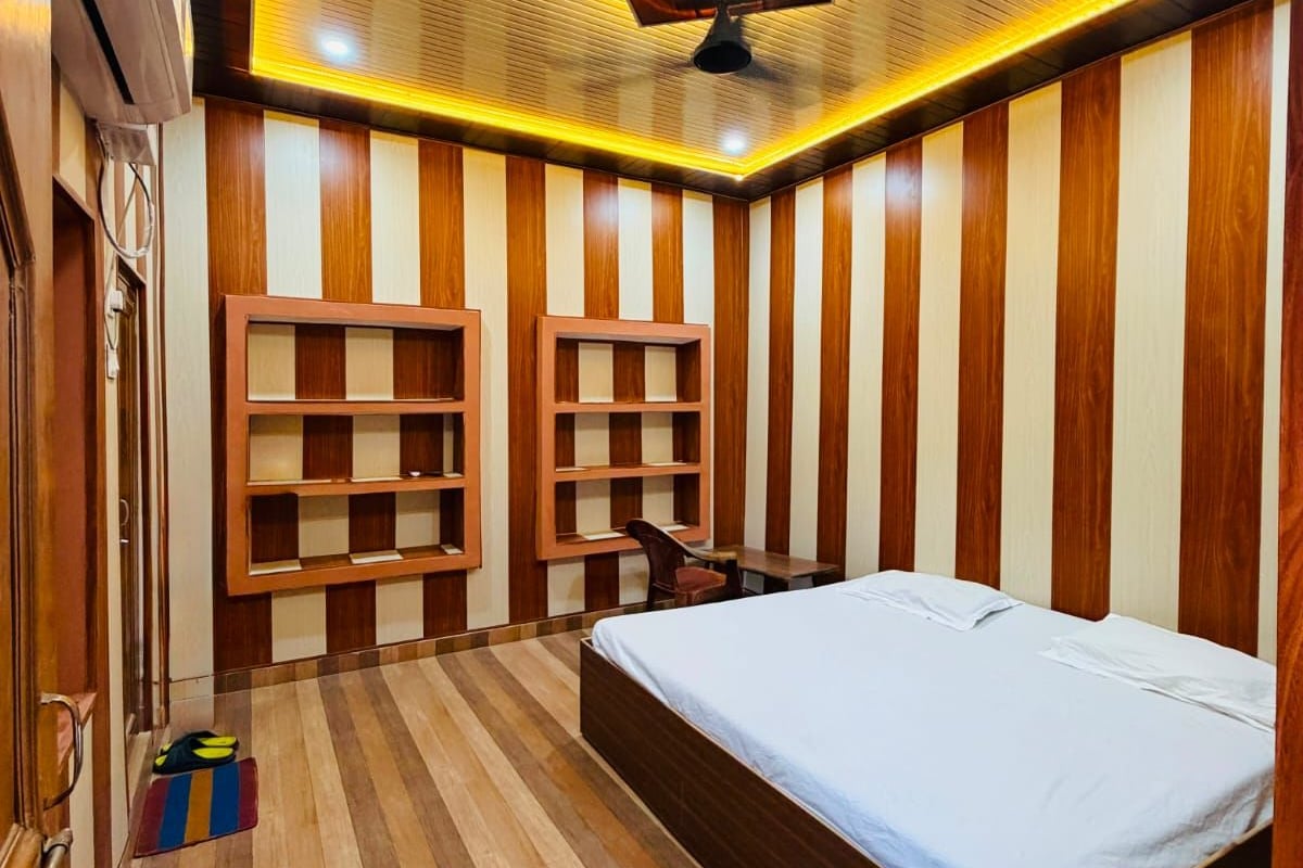 Una habitación con cama, estantes empotrados, ventilador de techo y piso de madera.