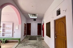 A corridor with a bench, a skylight, and a wooden door. - Malti Homestay (Varanasi)