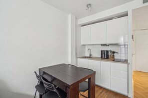 A compact kitchen with white cabinets, a wooden dining table, and a sink. - ID 306 - Champs Elysées / Rue Euler (Paris)