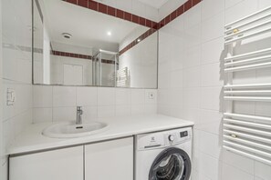 A modern bathroom with a sink, mirror, and washing machine. - ID 306 - Champs Elysées / Rue Euler (Paris)