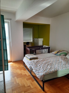Quarto com cama, escrivaninha e janela com persianas.