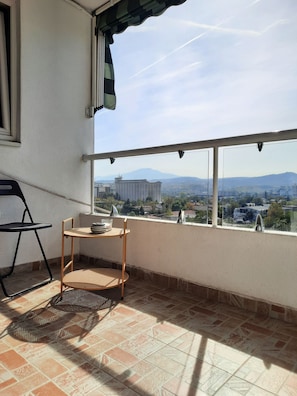 Uma varanda com vista para um horizonte urbano, incluindo edifícios e montanhas.