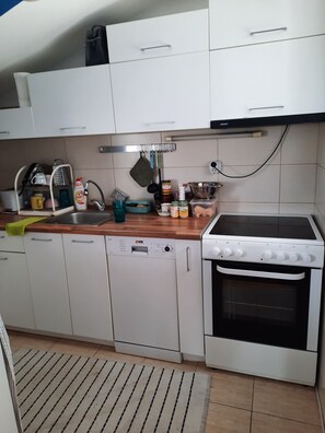 A kitchen with white cabinets, a dishwasher, an oven, and various kitchen utensils. - Cozy 1-bedroom apartment in tranquil Skopje with AC and free parking (Skopje)