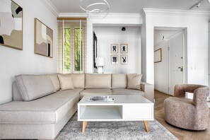 A modern living room with a sectional sofa, a white coffee table, and a patterned rug. - Whitewood Residence (Athina)