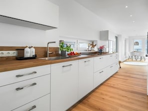 A modern kitchen with white cabinetry, a wooden countertop, and a built-in oven. - Apartment in Olpenitz With Swimming Pool (Kappeln)
