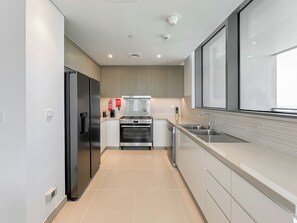 A modern kitchen with stainless steel appliances, a built-in oven, and a large window providing natural light. - Spacious Modern 3BR apartment in Dubai Marina, Sea View, Dubai Eye View (Dubai)