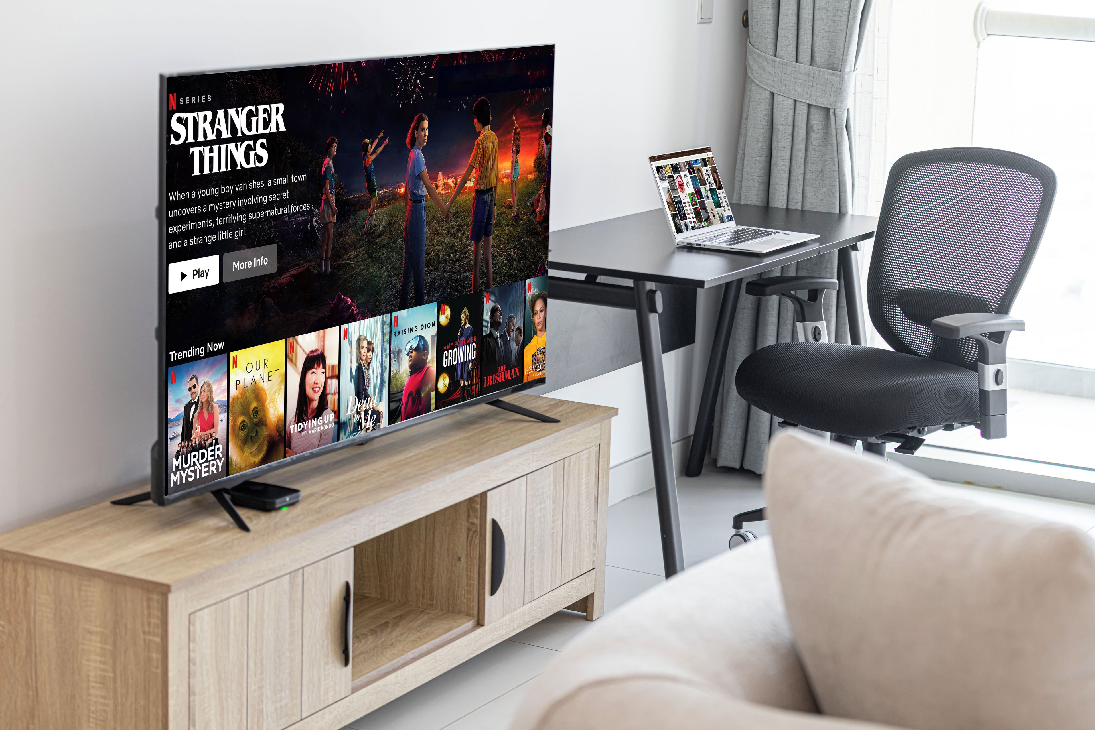 Televisão de tela plana em suporte de madeira exibindo a interface da Netflix com diversos programas.