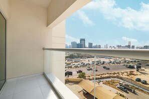 A balcony with a view of a parking lot and a city skyline. - Cozy 1BHK in Rabdan Motor City Dubai (Dubai)