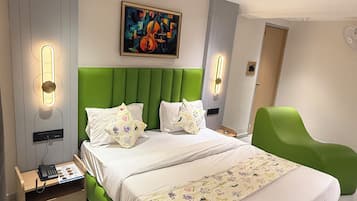 Una habitación de hotel moderna con una cama tapizada de verde, un cuadro en la pared y una mesita de noche con un teléfono.