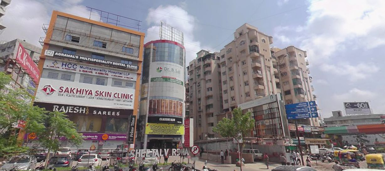 Una calle urbana concurrida, con edificios comerciales, incluyendo una clínica de estética y una clínica dental.