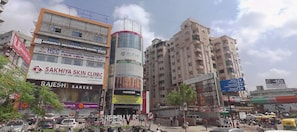 A busy urban street with commercial buildings, including a skin clinic and a dental clinic. - Hotel Pacific Icon (Ahmedabad)