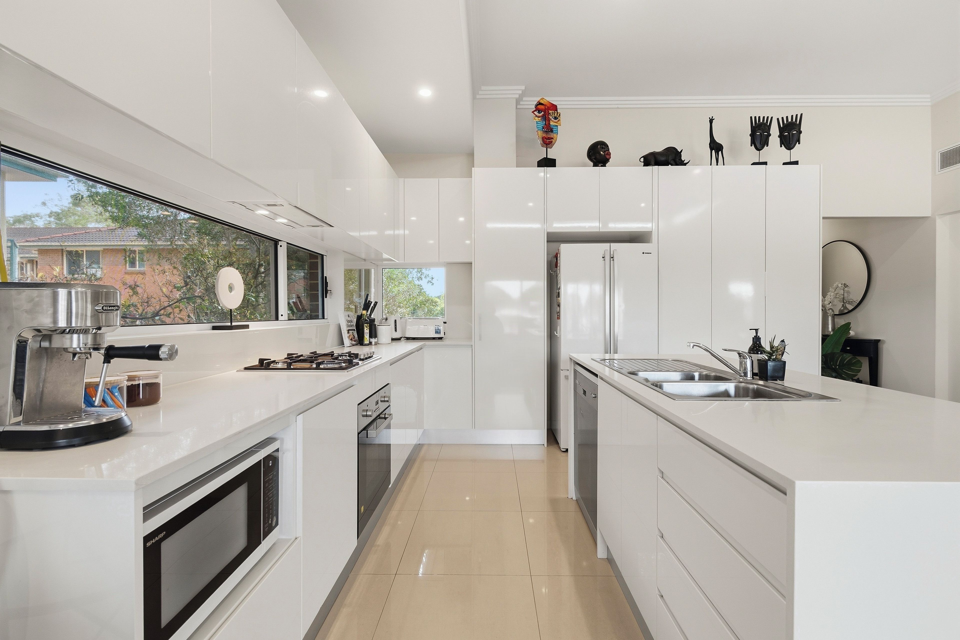 A modern kitchen with white cabinetry, a built-in oven, a gas stove, and a stainless steel sink.
