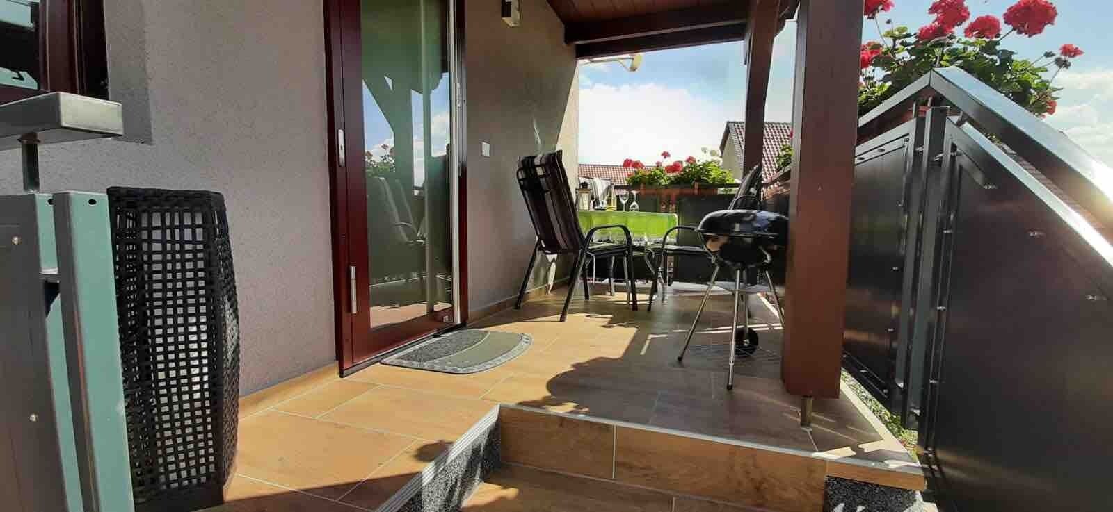 Un espace extérieur abrité, doté d’une table et de chaises, d’une porte-fenêtre coulissante et offrant une vue sur le ciel.