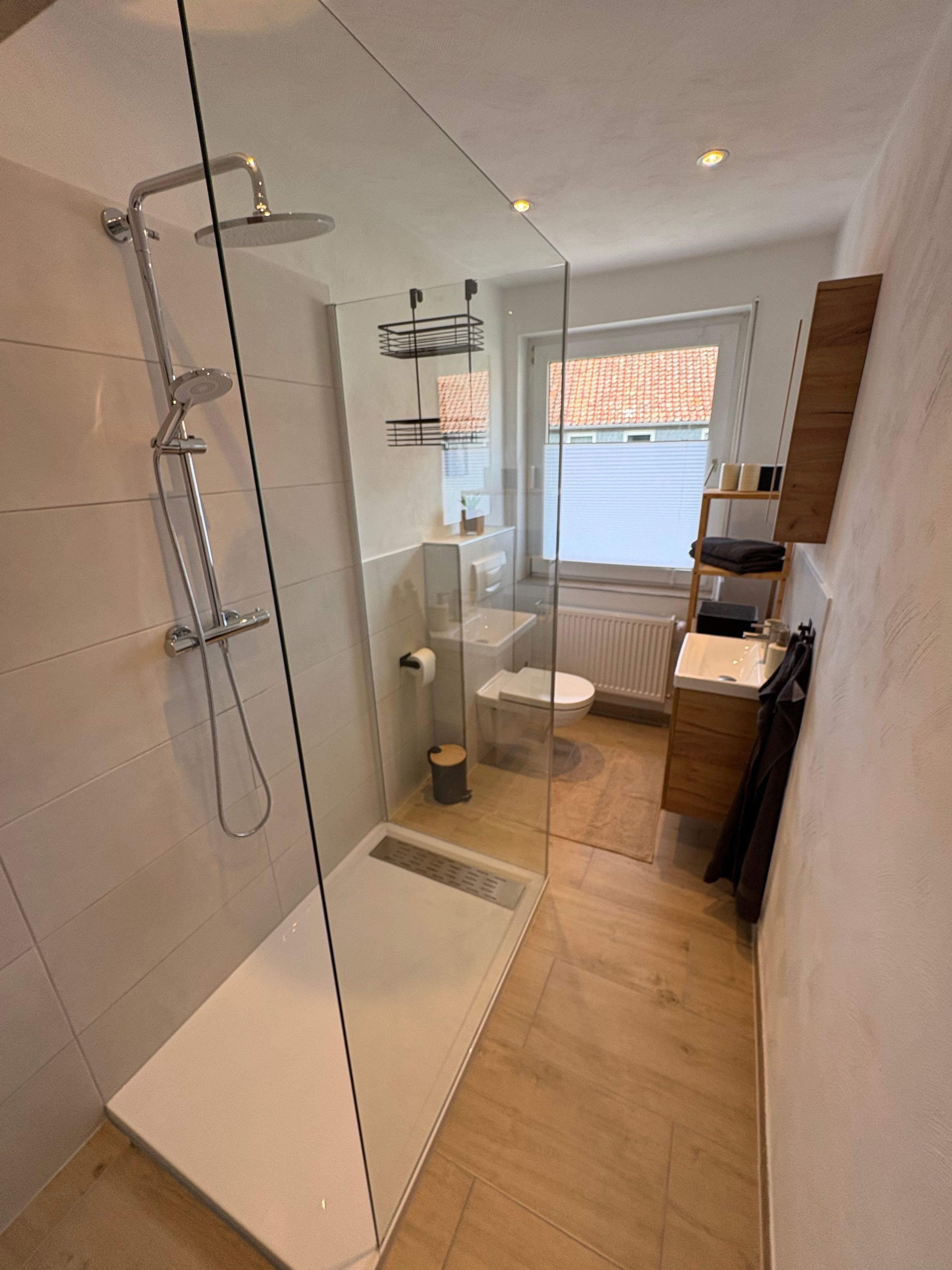 Ein modernes Badezimmer mit Duschkabine aus Glas, Toilette und Waschbecken.