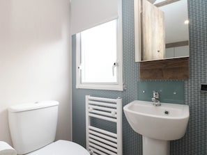 A bathroom with a toilet, a white radiator, and a sink with a mirror above it. - Brookwood Willerby, 36 Bay View (Filey)