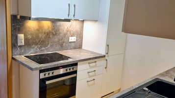 A kitchen with a built-in oven, a stovetop, and white cabinets.