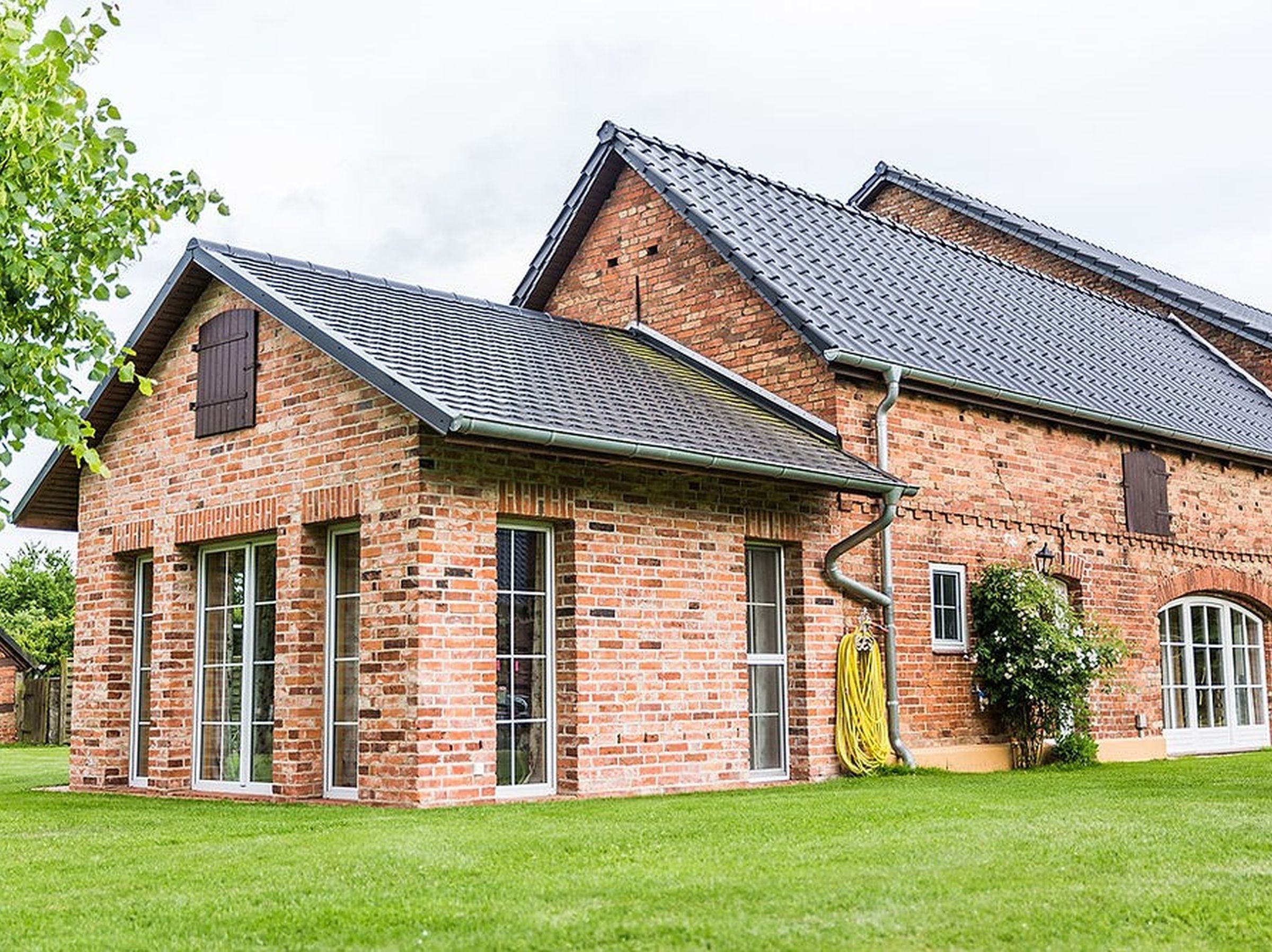 A brick building with large windows and a sloped roof.