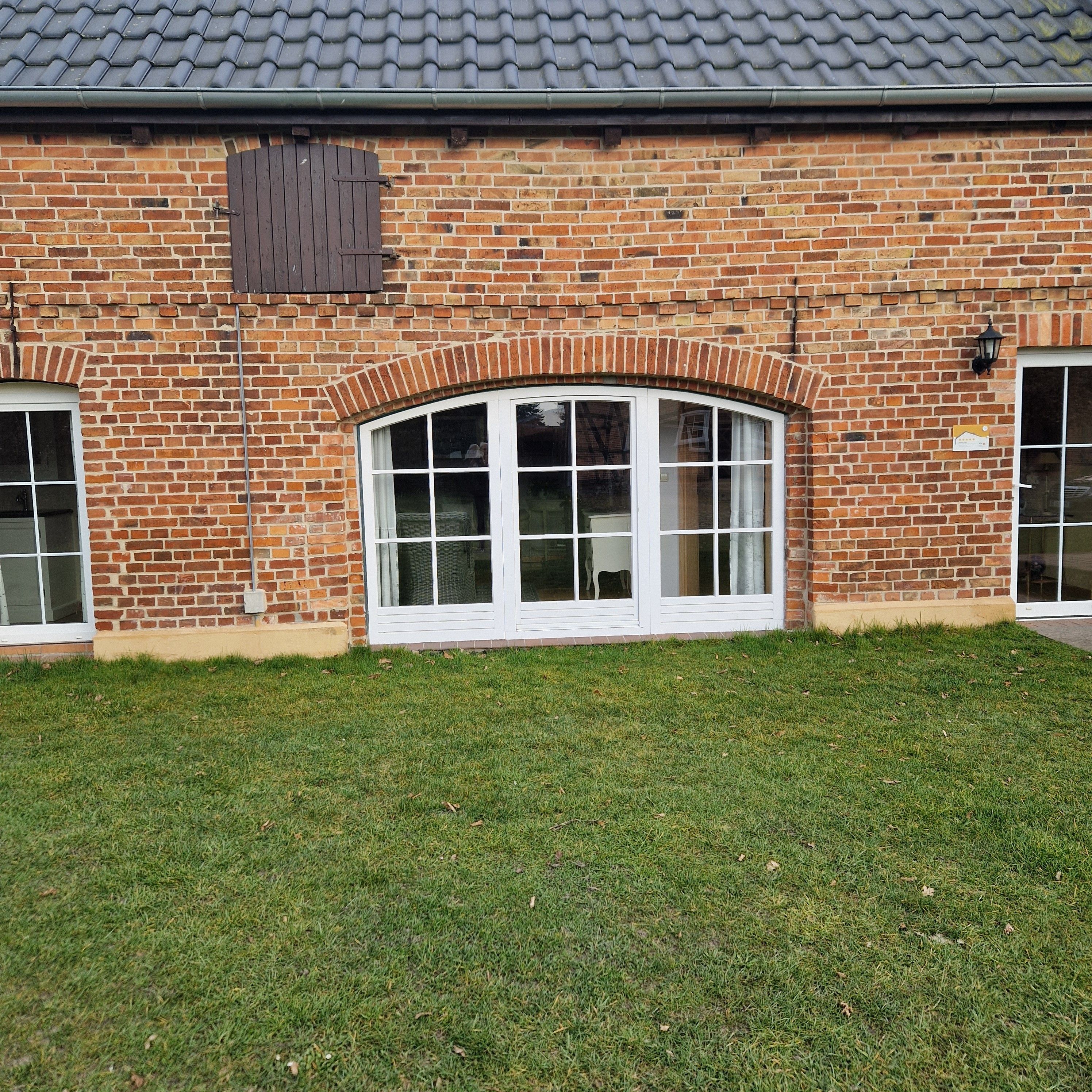 A brick building with a large arched window and a smaller window to the left.