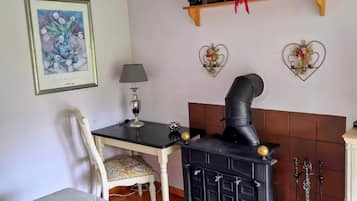 Una habitación con cama, una mesa con lámpara, chimenea y objetos decorativos en la pared.