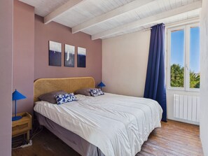 A bedroom with a bed, a nightstand, a lamp, and a window with curtains. - House for 6, pool & garden, walk everywhere (Noirmoutier-en-l´Ile)