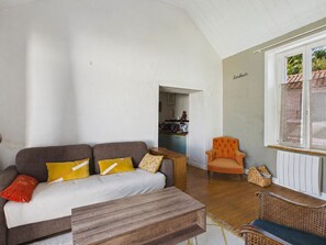 A living room with a sofa, a wooden coffee table, and a wicker chair. There is a kitchen visible in the background. - House for 6, pool & garden, walk everywhere (Noirmoutier-en-l´Ile)