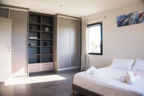Ein Schlafzimmer mit Bett, Kleiderschrank, Regale und einem Fenster.