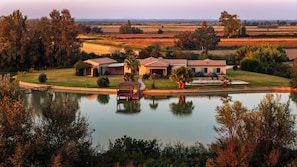 A large house with a swimming pool, surrounded by a well-maintained lawn and trees. - The House by the Pond in the Camargue (Arles)