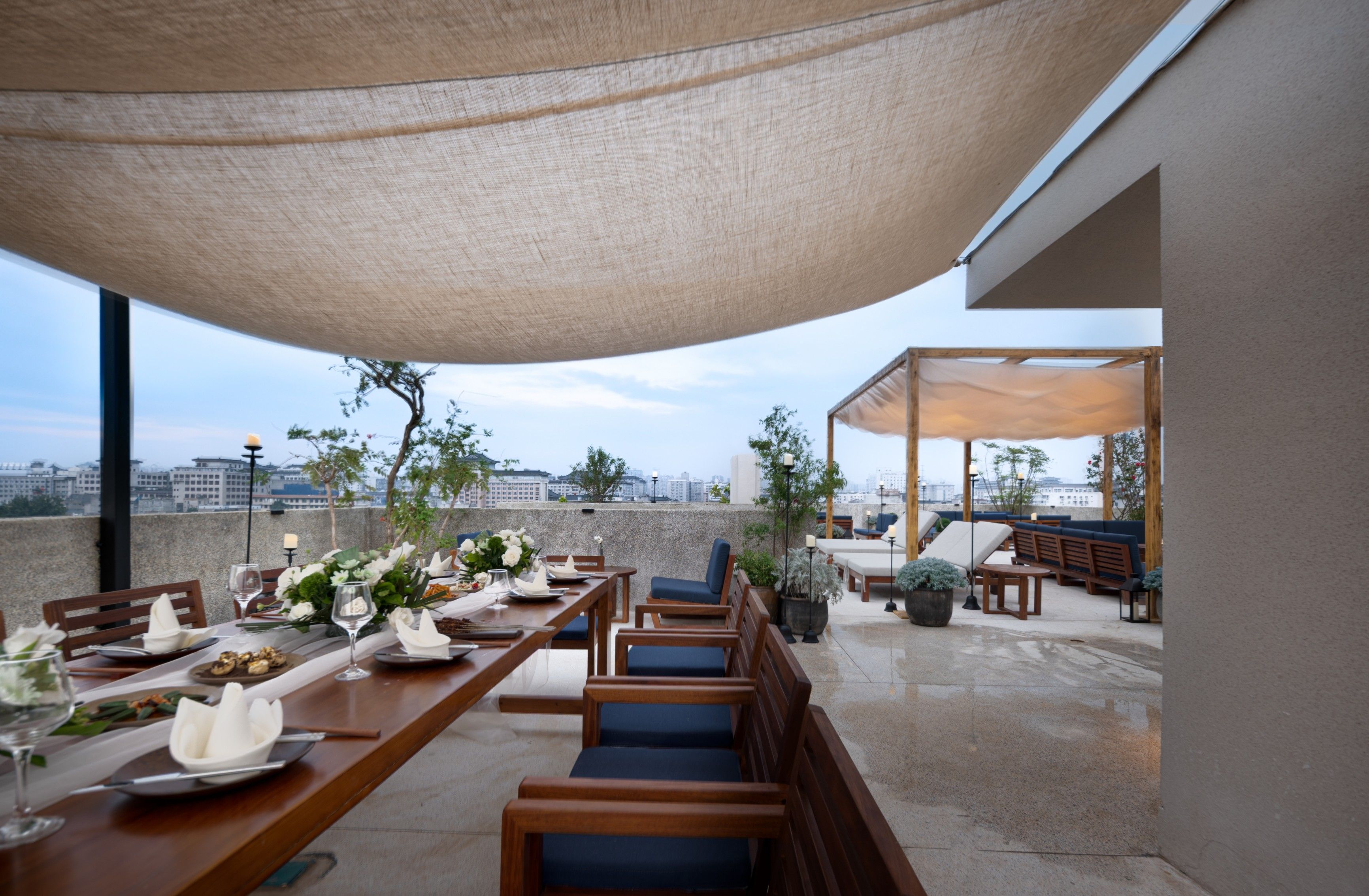 An outdoor dining area with a table set for two, surrounded by wooden chairs and a canopy overhead.