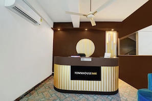 A reception desk with a 'RECEPTION' sign, a ceiling fan, and a patterned floor. - Hotel O The Dev Regency  (Patna)