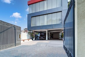 A modern building with a covered parking area and a gated entrance. - Hotel O The Dev Regency  (Patna)