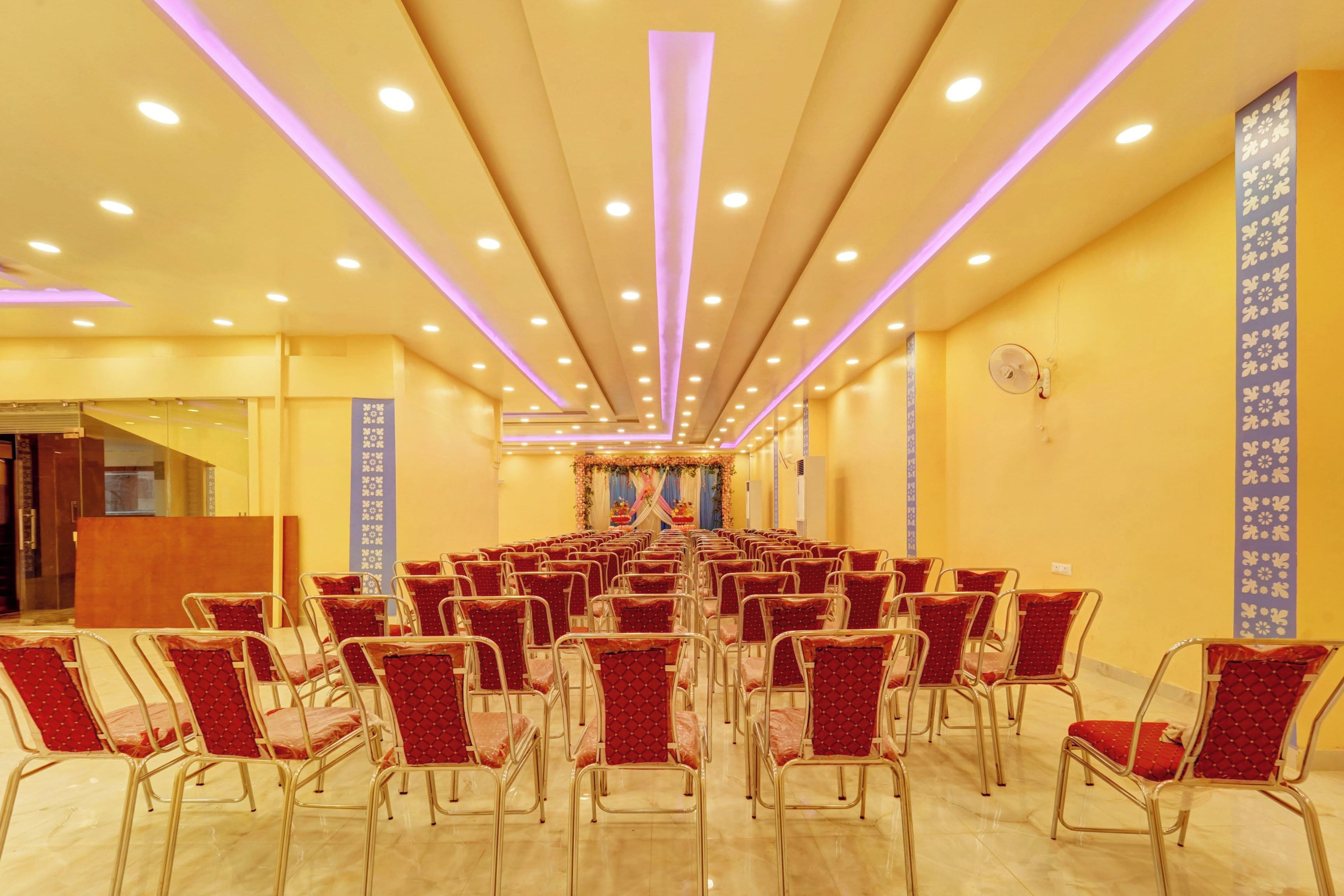 Un salón de conferencias con filas de sillas, un atril y un arreglo floral decorativo.