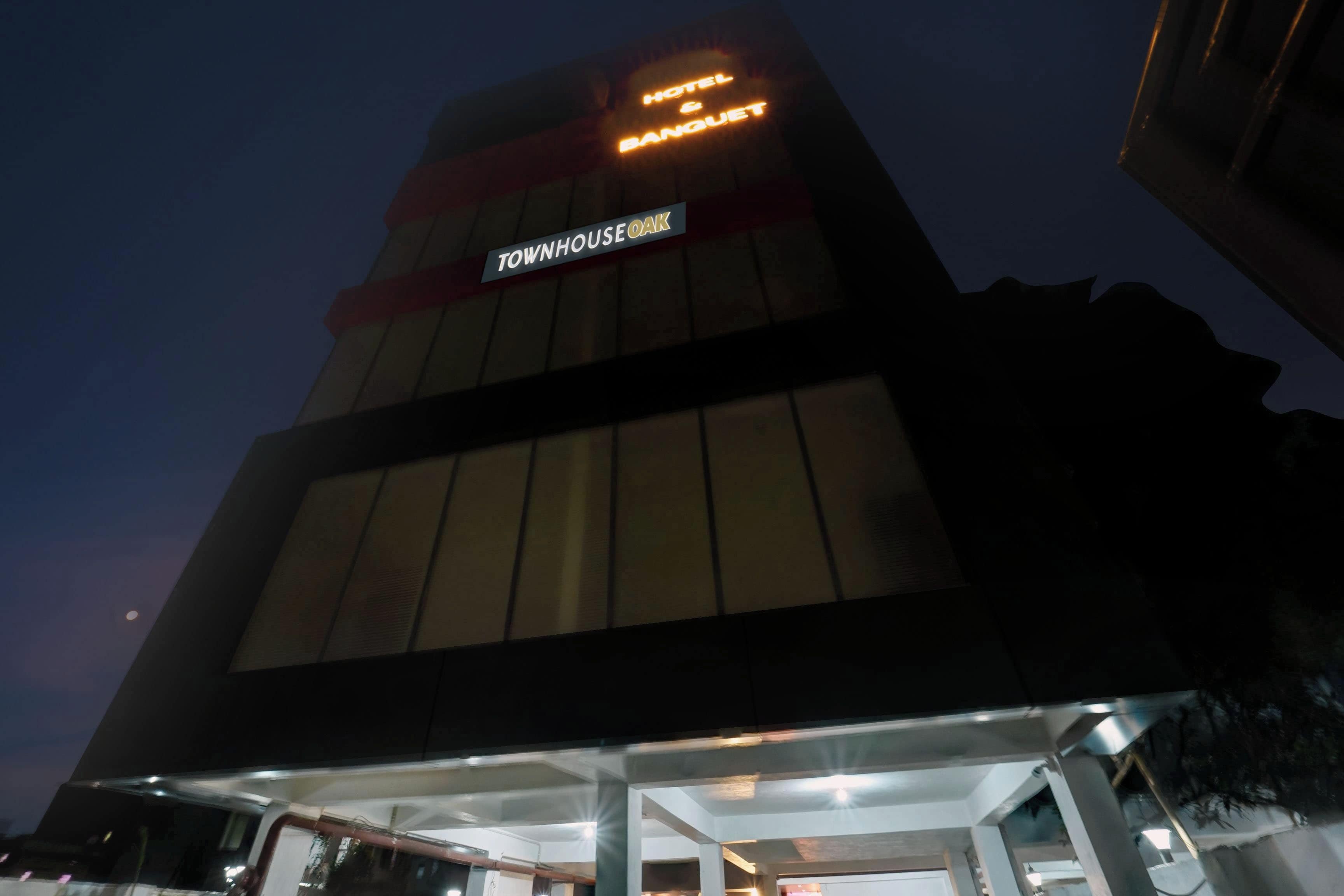 A hotel with a sign reading 'TOWNHOUSE OAK' and 'HOTEL & BANQUET' at the top.