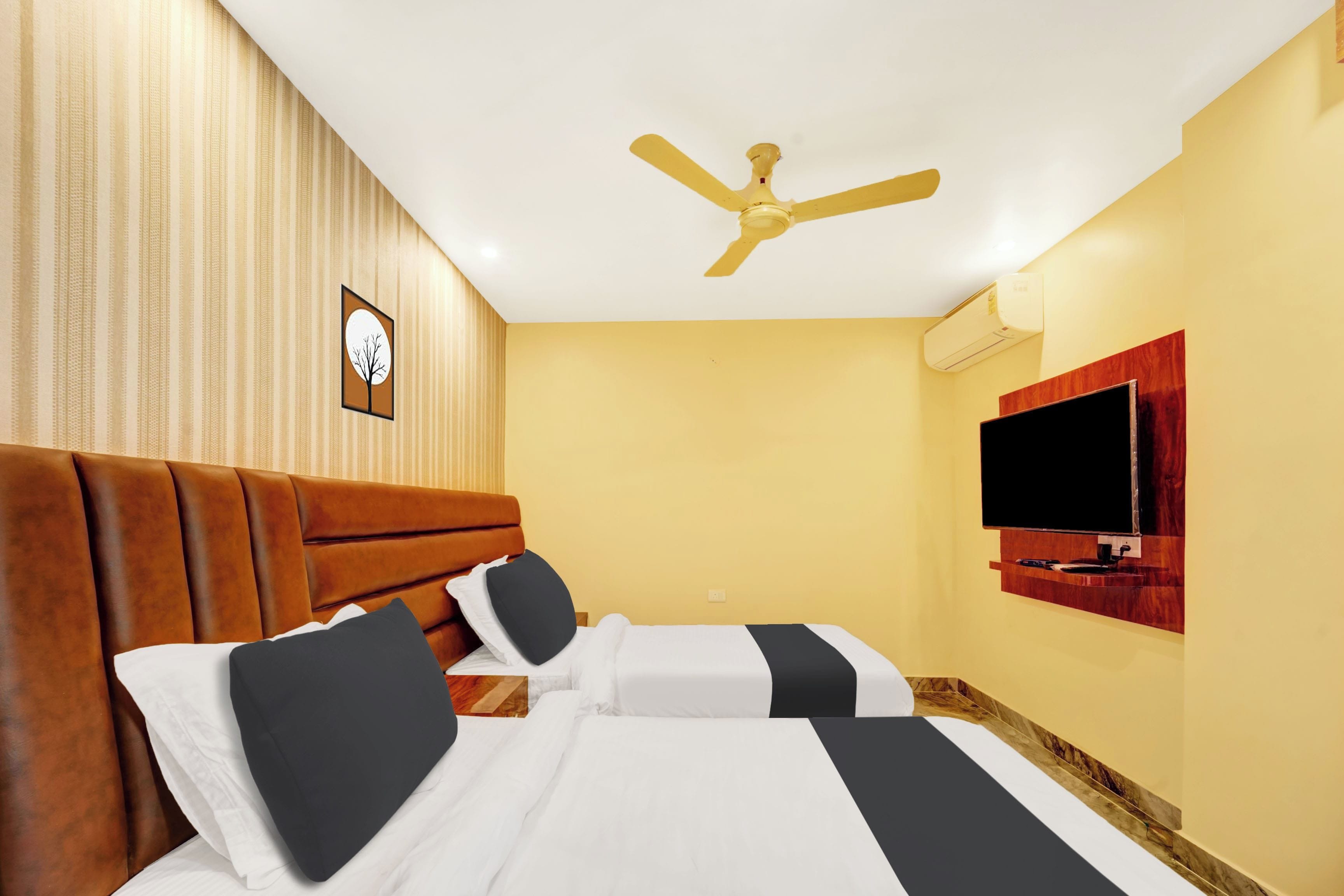 Camera d'albergo con un letto, una ventola a soffitto, una TV a parete e un condizionatore d'aria montato a muro.