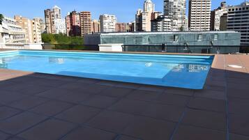 A rooftop swimming pool with a cityscape view.