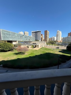 Un paysage urbain avec des bâtiments modernes, une zone verdoyante et un ciel dégagé.