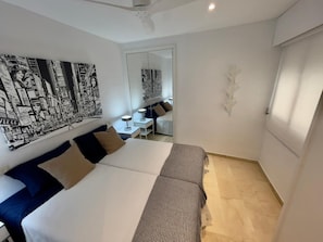 Une chambre d’hôtel avec un grand lit, un bureau et une chaise. Il y a un grand tableau au mur et un miroir.