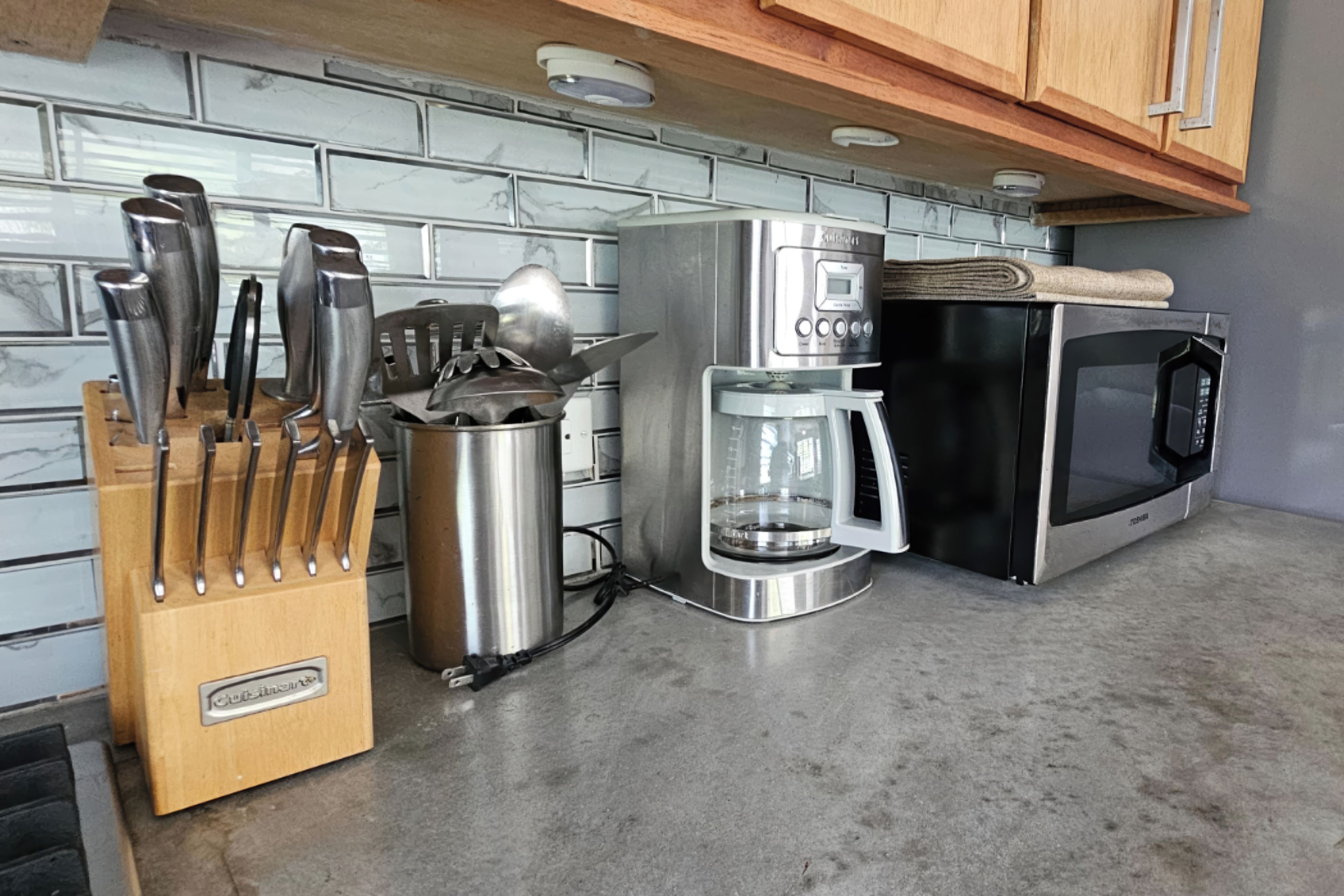 A kitchen with a coffee maker, microwave, and knife block.