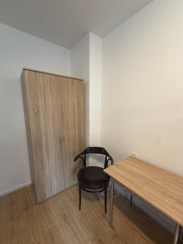 Ein Zimmer mit einem Holfischschrank, einem schwarzen Stuhl und einem Holztisch.